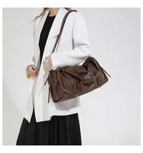 Detail of dark brown leather pillow bag featuring fringe tassels and metal ring accents