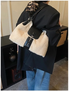 Detail of soft plush shoulder bag featuring contrast black faux leather trim and buckle