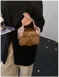 Detailed macro view of brown quilted handbag with silk scarf handle and golden hardware