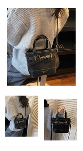 Detail view of black leather crossbody bag with gold hardware and reinforced handle