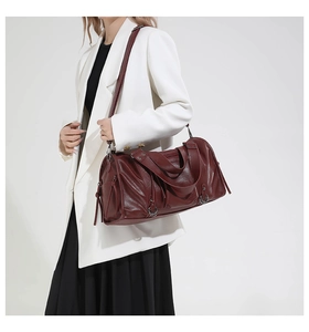 Detail of burgundy leather boston bag featuring soft folds and silver fringe zipper pulls