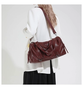 Detail of burgundy PU leather pillow bag with metal rings and fringe on a model