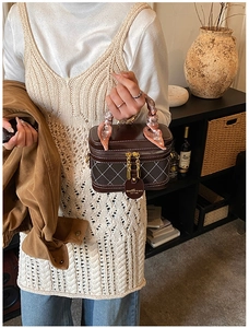 Close-up of brown quilted box bag with silk scarf handle and vintage aesthetic