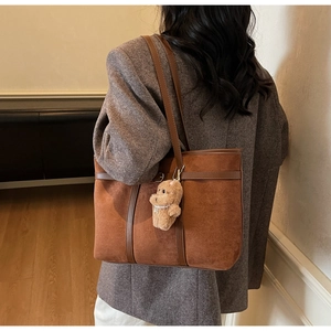 Detail of vintage brown suede tote bag with plush bear charm and leather handles