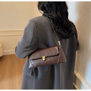 Rear view of a model wearing a brown minimalist baguette bag with gold metal buckle