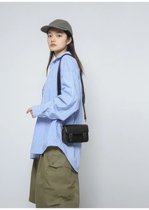 Detail of a black faux leather crossbody bag featuring vintage double buckle flap design