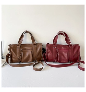 Detail of vintage Maillard duffel bags in caramel and burgundy with rivet and tassel accents