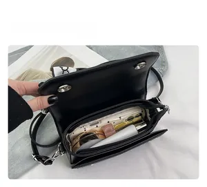 Interior space of a black leather crossbody bag showing compartments and daily essentials