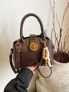 Retro dark brown shell-shaped crossbody bag with gold twist lock and bead charm decor
