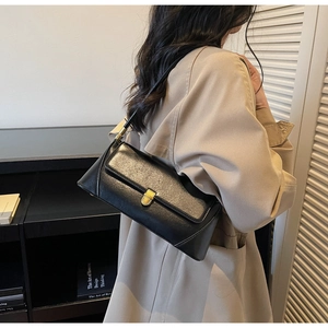 Detailed side view of a black baguette bag with gold hardware on a model for urban style
