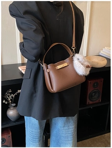 Detail of dark brown lychee grain leather bucket bag with gold lock and plush bunny charm