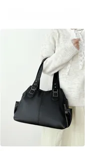 Close-up of black lychee-grain leather tote bag with silver metal buckles on model