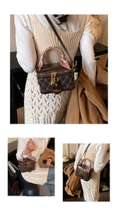 Detail of dark brown box bag with white stitching, gold hardware and silk scarf handle