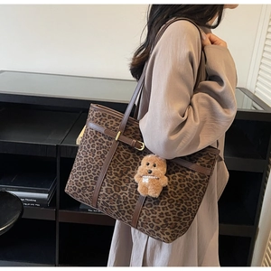 Detail of leopard print suede tote bag with brown leather trim and plush puppy charm