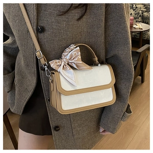 Detail of canvas crossbody bag with silk scarf handle on a plaid blazer outfit