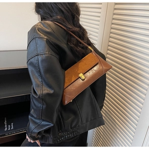 Detail of vintage brown baguette bag featuring contrast leather and gold buckle closure