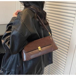 Detail of dark brown baguette bag with suede leather mix and gold metal buckle lock