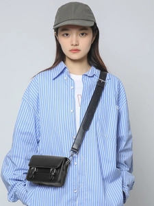 Minimalist black leather crossbody camera bag shown on model with adjustable strap