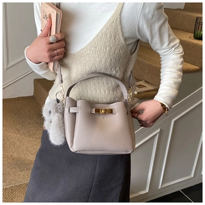 Detail of apricot pebbled leather bucket bag with gold clasp and plush rabbit charm