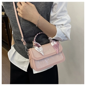 Detail of pink crossbody bag featuring a silk scarf-wrapped handle and flap closure