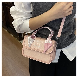 Detail of pink crossbody bag with printed silk scarf handle and metal fashion logo