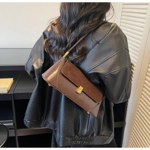 Brown vintage baguette bag featuring smooth leather and suede panels with a gold metal lock