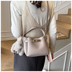 Detailed view of grey lychee leather bucket bag with gold lock and plush rabbit charm