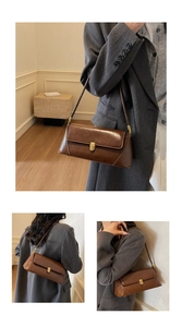 Close-up of brown glossy leather baguette bag featuring a gold metal buckle and thin strap