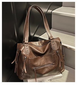 Detail view of large dark brown soft leather tote bag with stylish zipper pockets