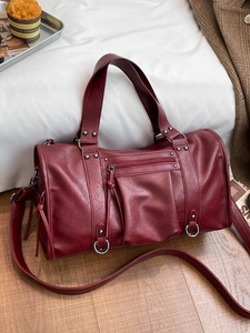 Vintage burgundy pillow bag with rivets and shoulder strap on a cozy indoor background