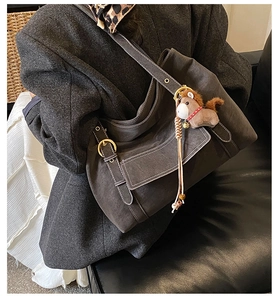 Détail macro du grand sac cabas en daim gris avec boucle dorée et breloque petit cheval