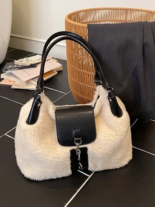 Winter faux fur handbag with black leather trim and top handle in a cozy interior setting