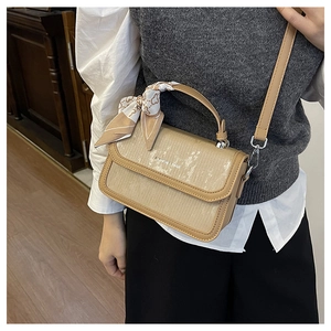 Detail of khaki square handbag with striped pattern and silk scarf handle on model
