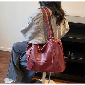 Detail of dark red vintage tote bag with multiple zip pockets and rivet hardware
