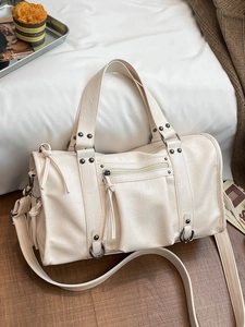 Chic beige hobo bag with silver studs and adjustable strap on a cozy background