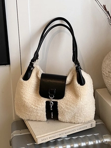 Winter faux fur tote bag in creamy white with black leather handles on a silver suitcase