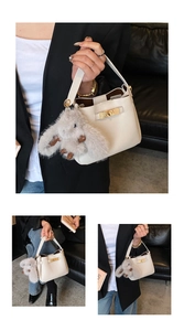 Detail view of cream lychee leather bucket bag with plush rabbit charm and gold twist lock