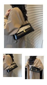 Detail of a black leather baguette bag featuring a gold twist lock and slim shoulder strap