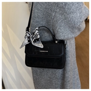 Detail of black corduroy handbag with fashion print silk scarf on the handle