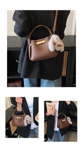 Deep brown lychee leather bucket bag with gold clasp and plush rabbit pendant