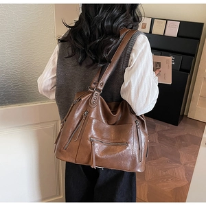 Detail of vintage brown leather tote bag showing multi-pocket design and metal zippers