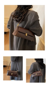 Detail of dark brown baguette bag with golden metal twist lock and wax leather texture