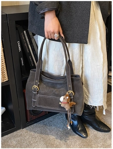 Détail du cabas en daim gris foncé avec surpiqûres et charm décoratif en forme de cheval