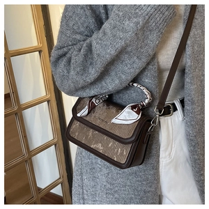 Brown striped leather crossbody bag with chic black and white scarf detail on handle