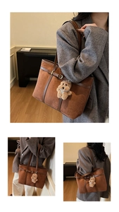 Detailed view of brown suede tote bag featuring leather straps and a plush bear charm