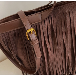 Détail du sac cabas en daim marron foncé avec de longues franges et boucle dorée
