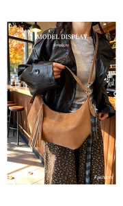 Detail of khaki leather dumpling bag featuring trendy side tassels and rivet strap