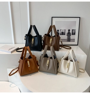 Close-up of five leather bucket bags in neutral tones with gold hardware on white steps