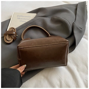 Detail der braunen Vintage-Eimertasche aus glänzendem Öl-Wachs-Leder mit Griff und Gurt