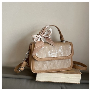 Detail of a vintage-style crossbody bag with silk scarf on handle and metallic clasp
